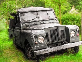 A weathered Land Rover Series parked in woodland, the kind of car whose mechanics a driver was expected to understand and repair